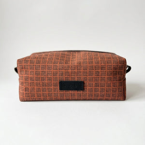 Brown checkered toiletry bag with a black label on a white background