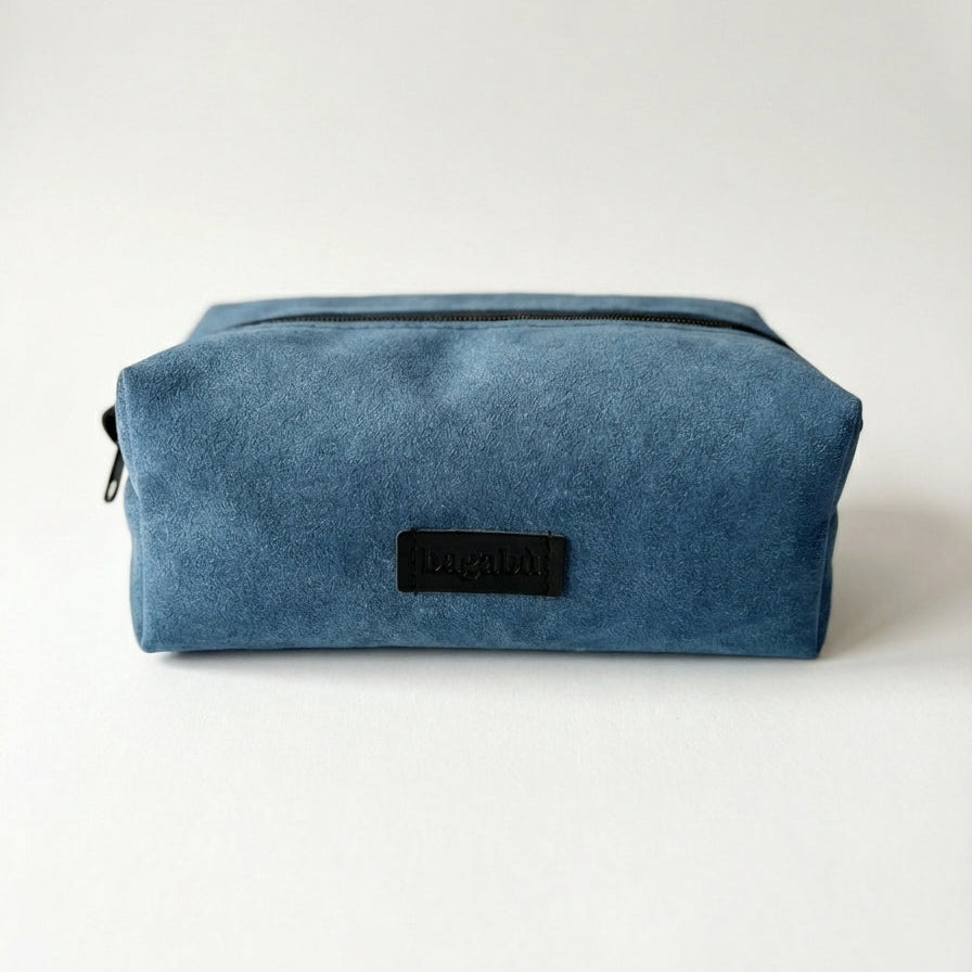 Blue toiletry bag with a black label on a white background