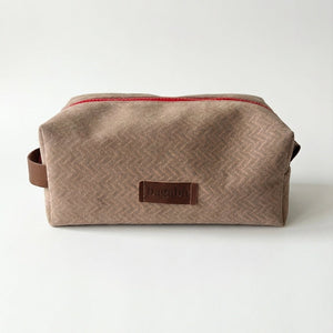 Brown toiletry bag with a visible brand logo on a white background