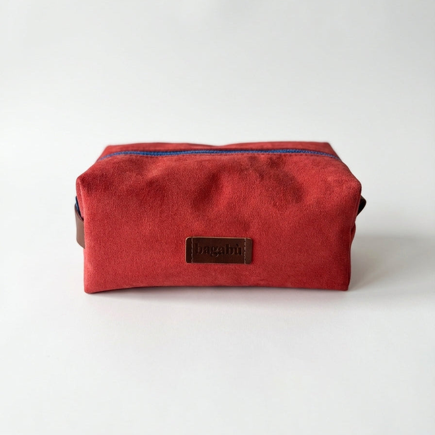 Red toiletry bag with a brand label on a white background