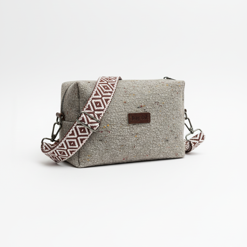 Gray textured handbag with a patterned strap on a white background