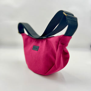 Pink bag with a black strap on a white background