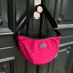 Pink bag with a visible brand label attached to a dark metal surface.