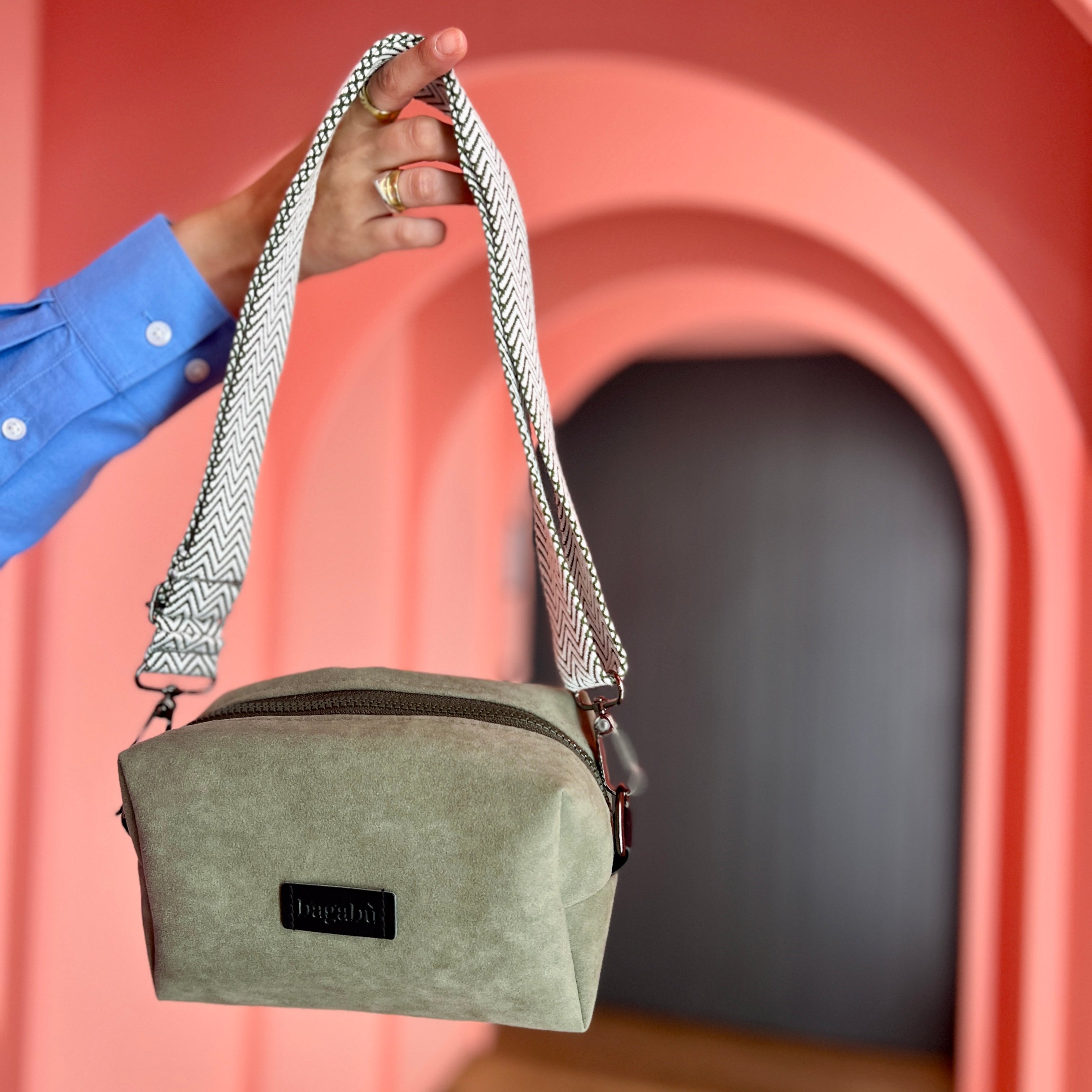 Person holding a green bag with a pink archway in the background