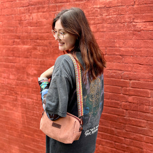Woman with a pink bag standing against a red brick wall