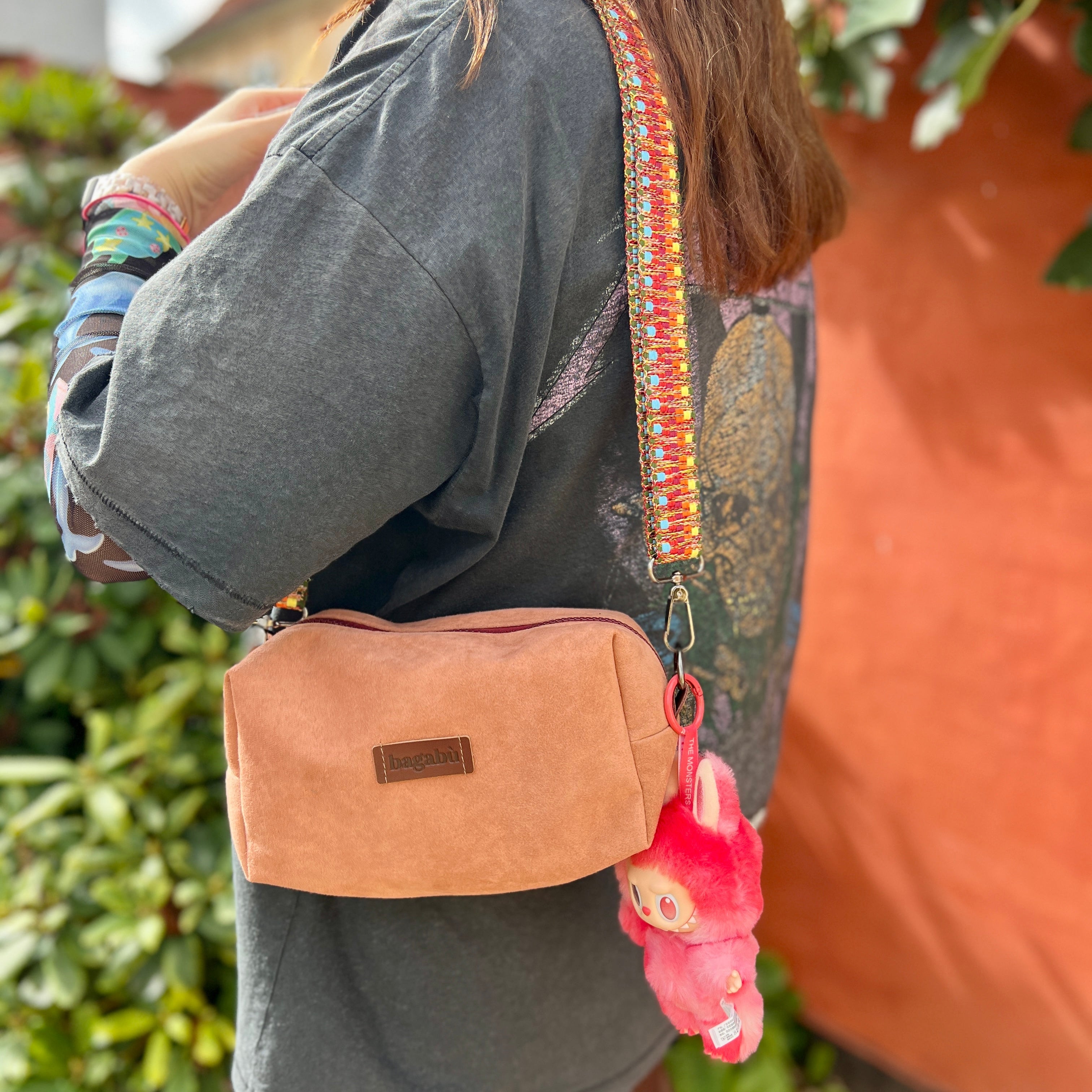 Person wearing a brown crossbody bag with a colorful strap outdoors.