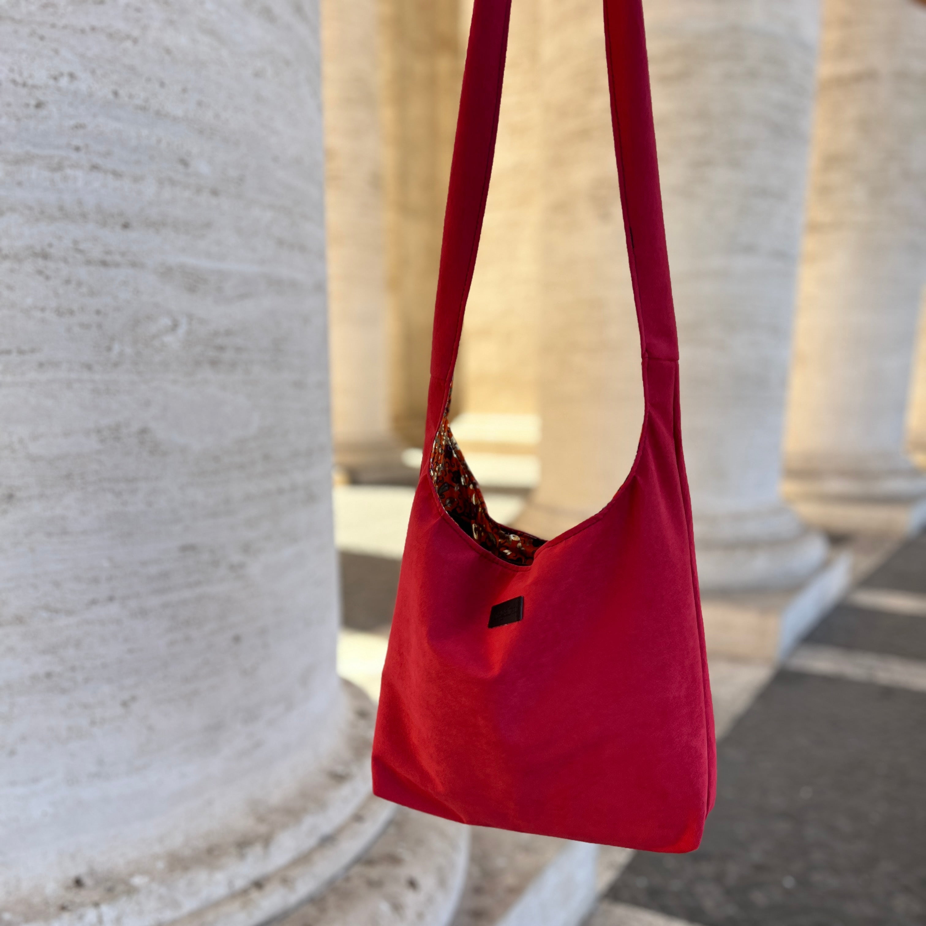 Red handbag hanging on a stone column outdoors