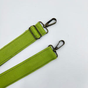 Two lime green adjustable shoulder straps with metal buckles, laid out on a white background.