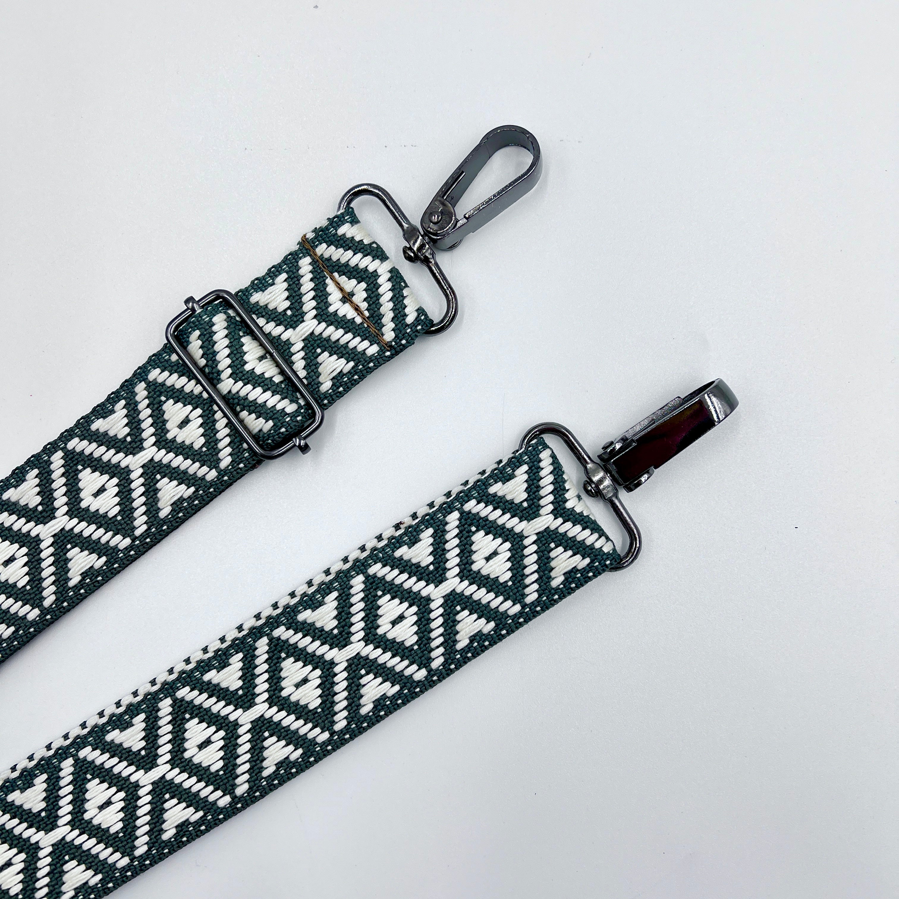 Two adjustable shoulder straps with a geometric pattern, primarily in gray and white, lying flat against a white background.