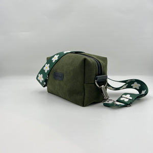 A green canvas picnic backpack with a floral pattern on the strap, displayed against a white background.