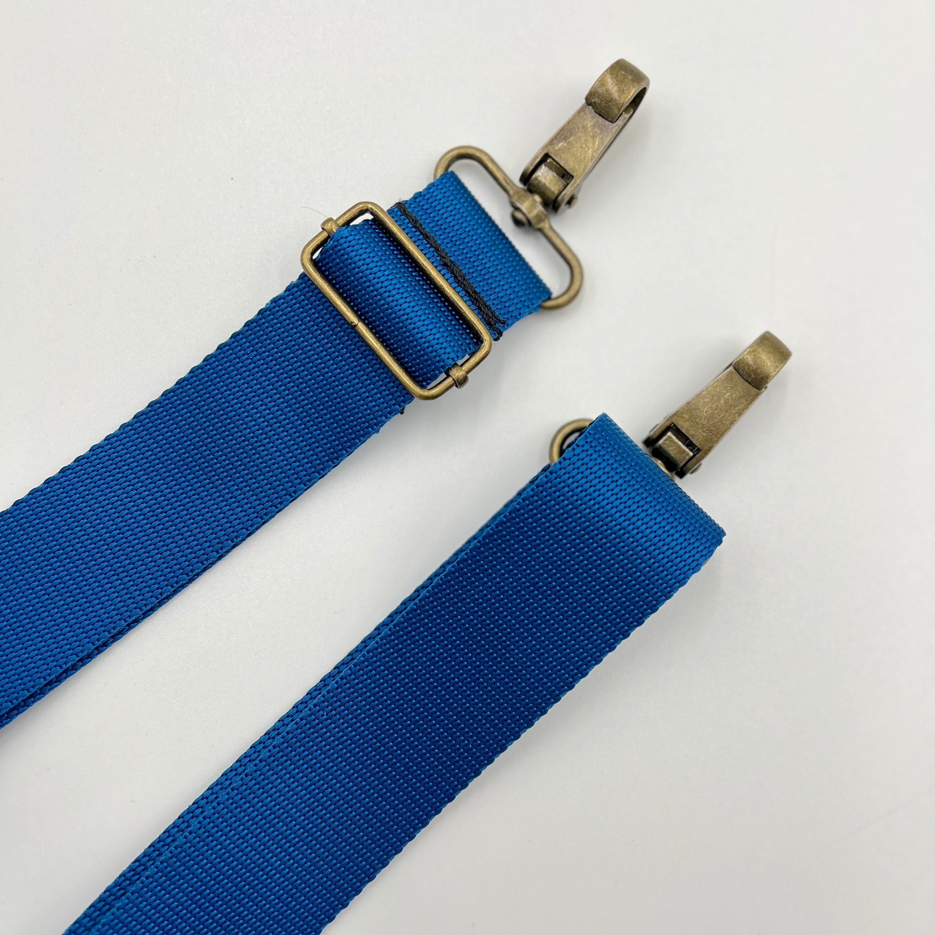 Two dark blue adjustable shoulder straps with metal buckles, isolated on a white background.