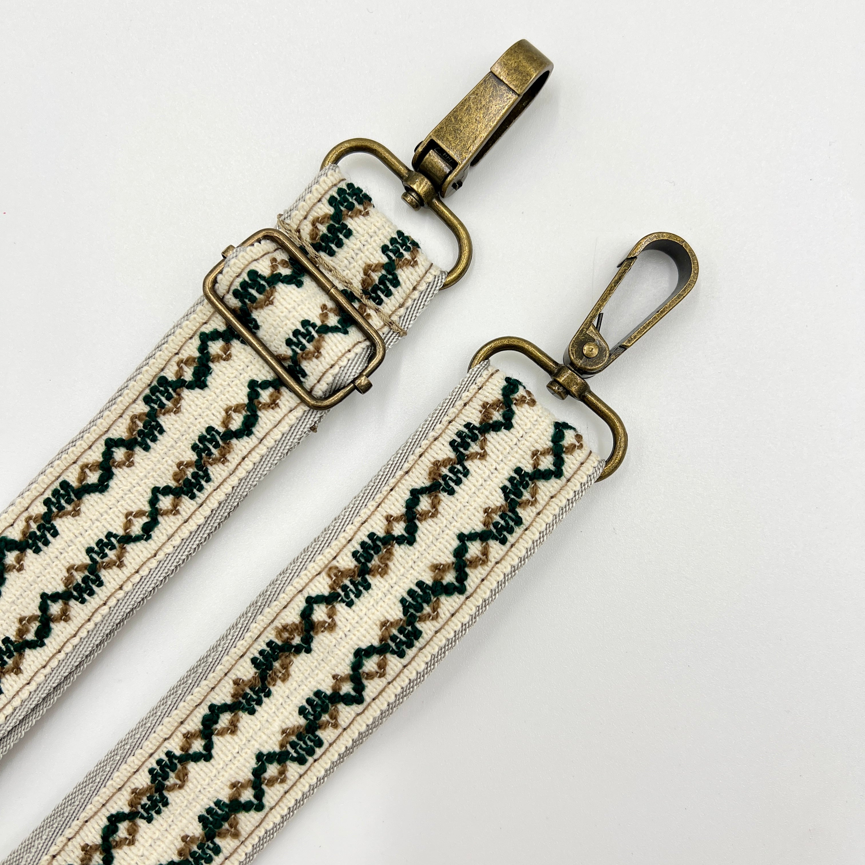 Adjustable shoulder strap with beige, green, and black embroidery and metal hardware