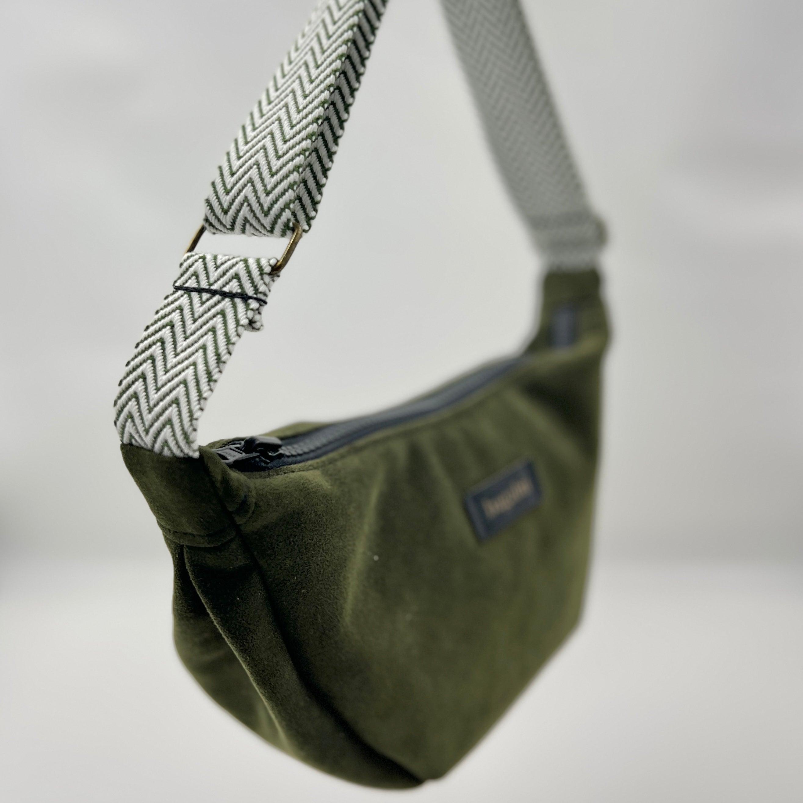 Green shoulder bag with patterned strap on a neutral background