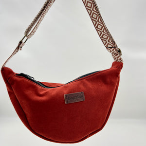 Brown shoulder bag with patterned strap on a neutral background