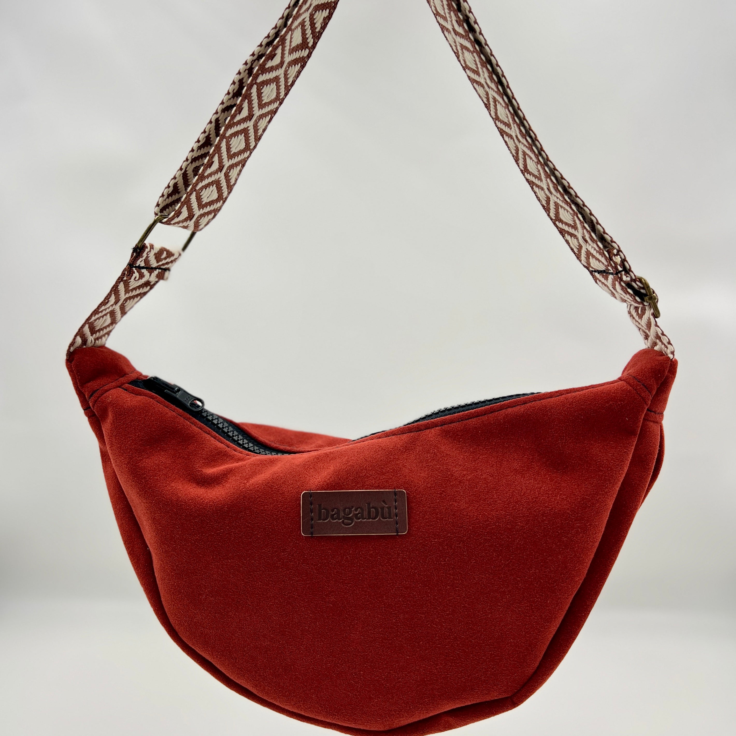 Brown shoulder bag with patterned strap on a neutral background