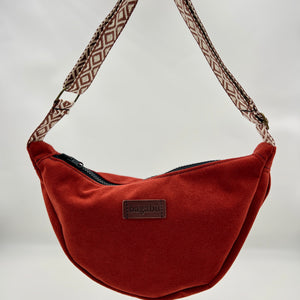 Brown shoulder bag with patterned strap on a neutral background