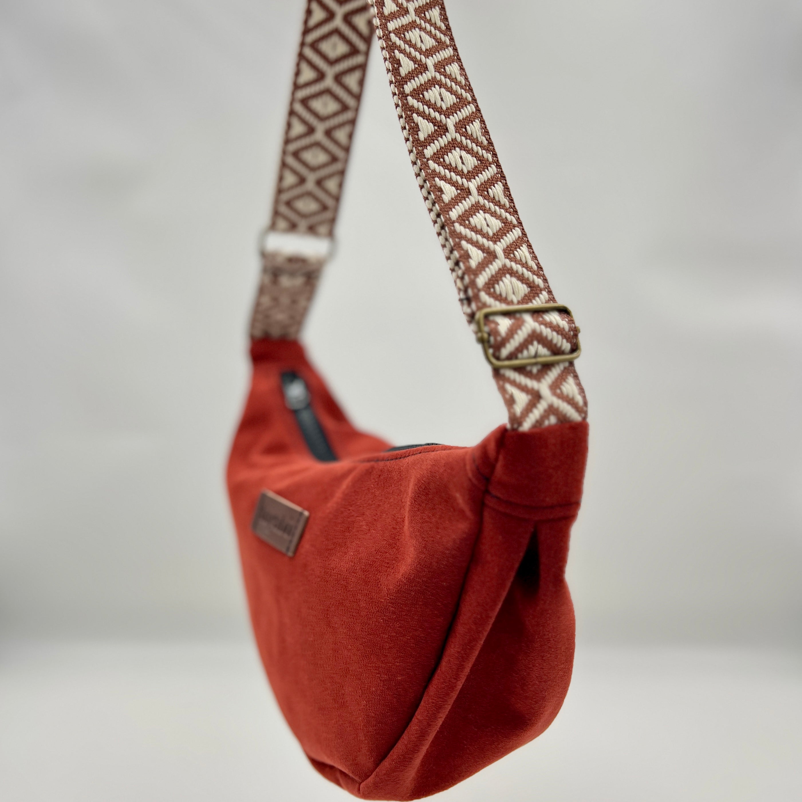 Brown bag with a patterned strap on a neutral background