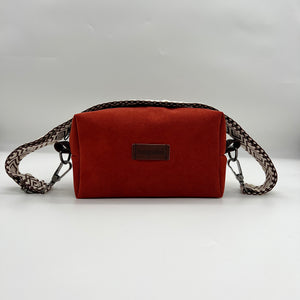 A red faux leather handbag with a textured pattern and a brand label on the front.