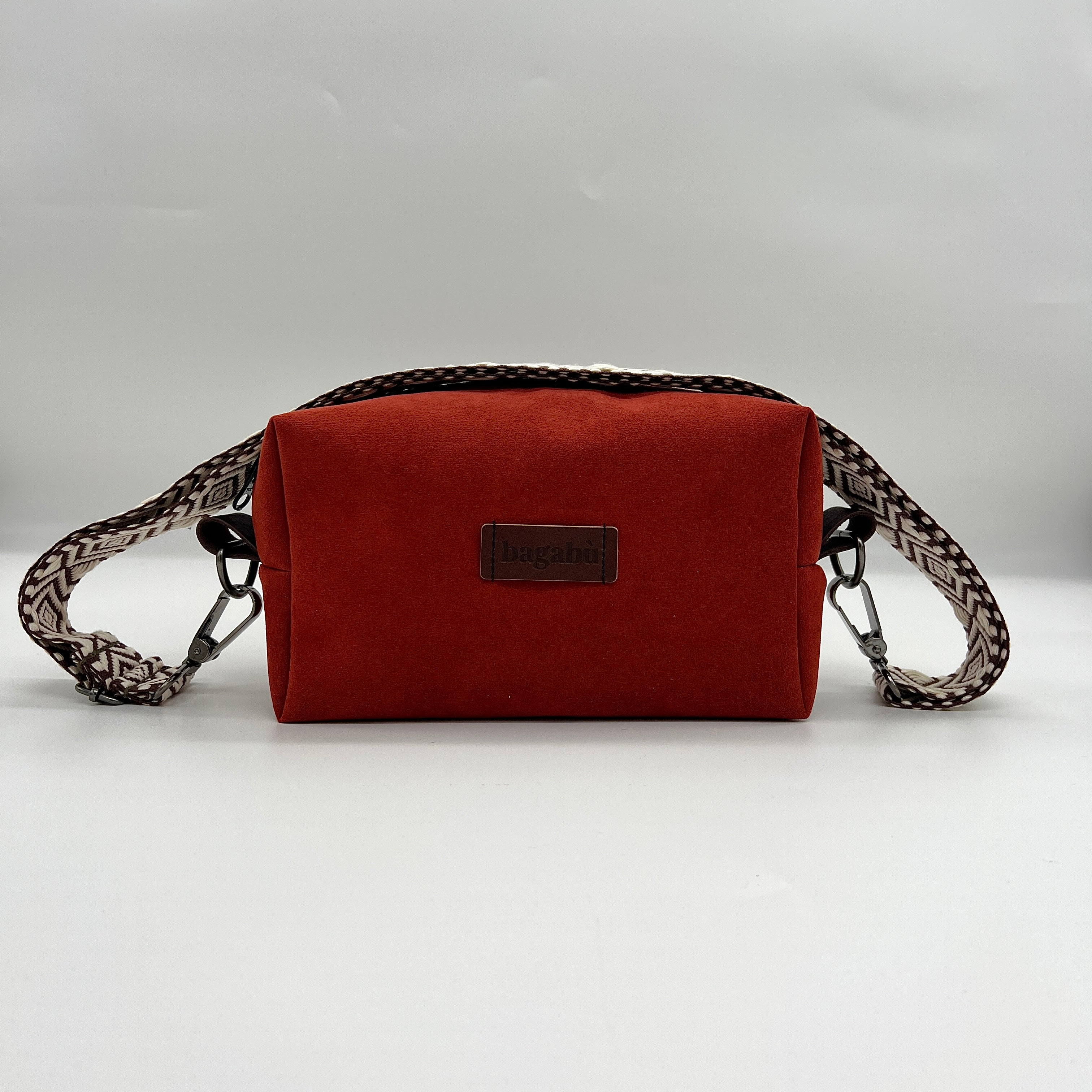 A red faux leather handbag with a textured pattern and a brand label on the front.