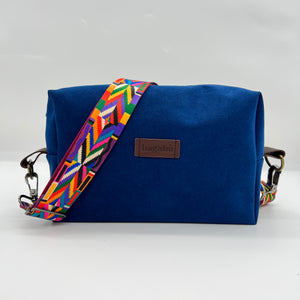 A blue shoulder bag with a colorful geometric patterned strap, displayed against a white background.