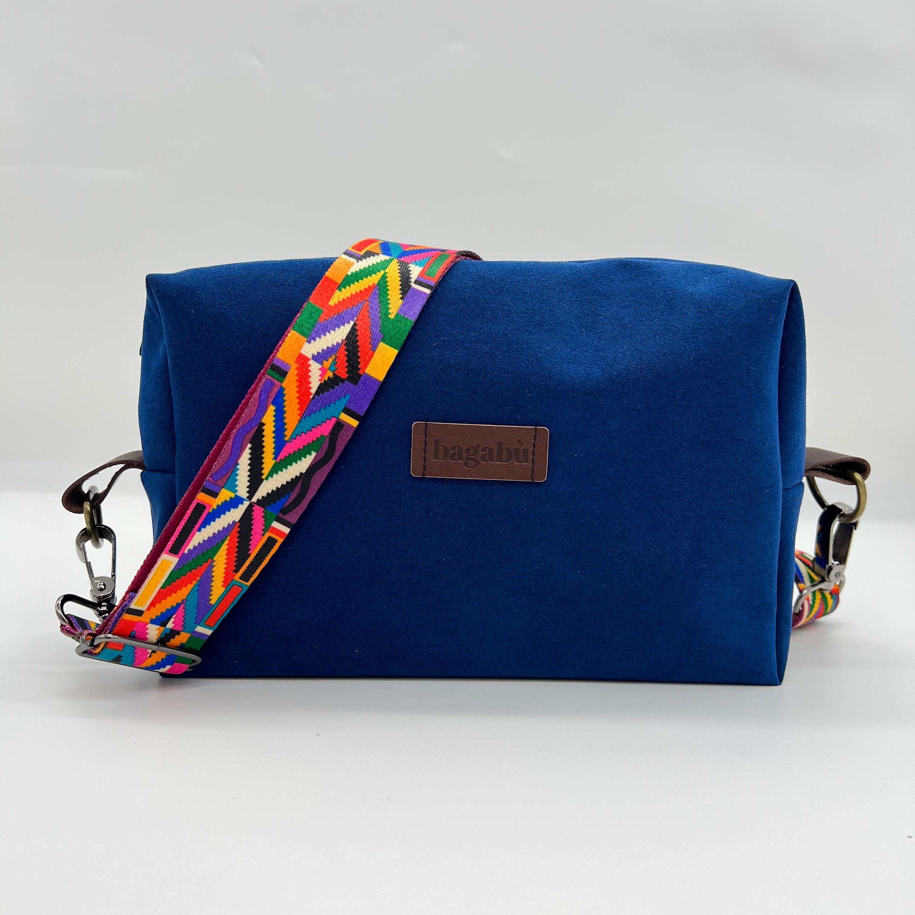 A blue shoulder bag with a colorful geometric patterned strap, displayed against a white background.