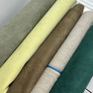 Rolls of fabric in various colors stacked on a flat surface