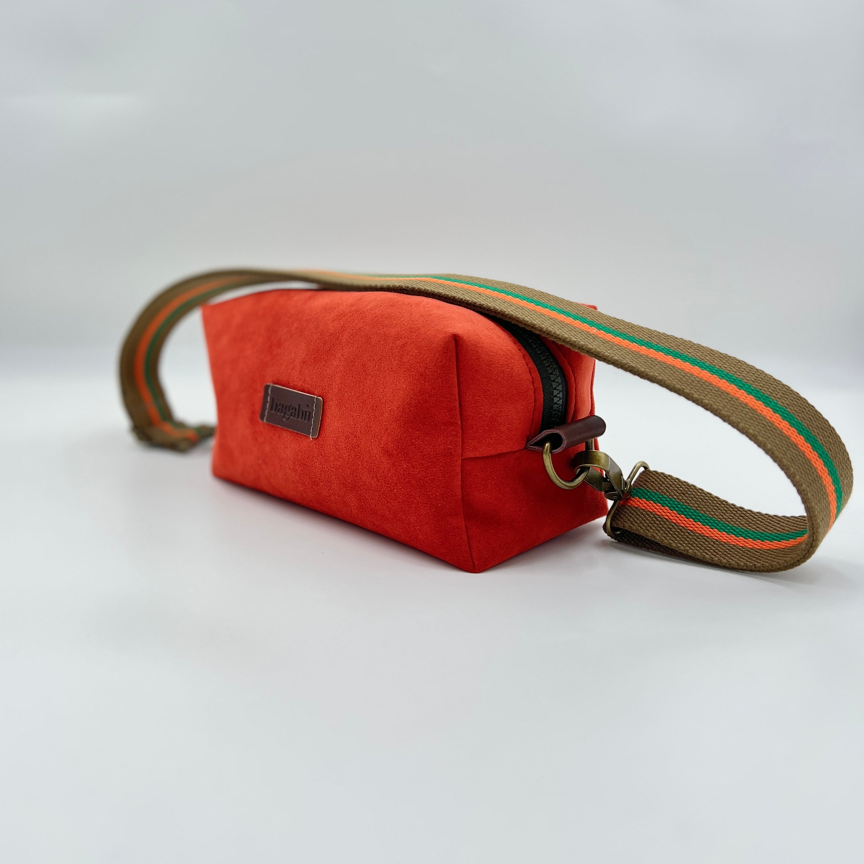 Orange pouch with a striped strap on a light gray background