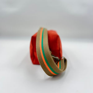 Brown bag with a green and orange striped strap on a white background