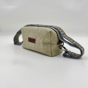 Beige handbag with a dark strap on a light gray background