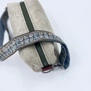 Close-up of a beige bag with a decorative strap on a white background