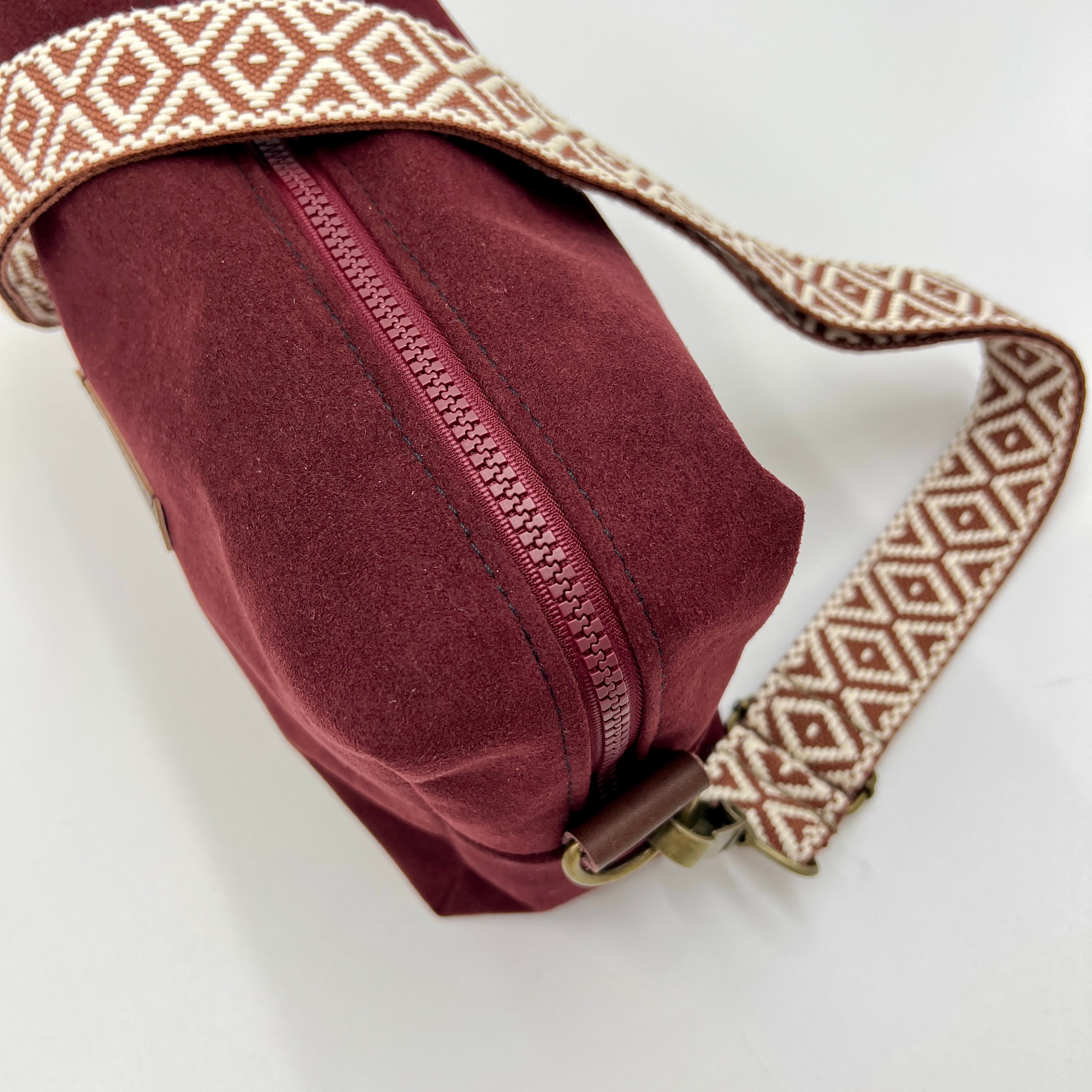 Maroon bag with a patterned strap on a light background