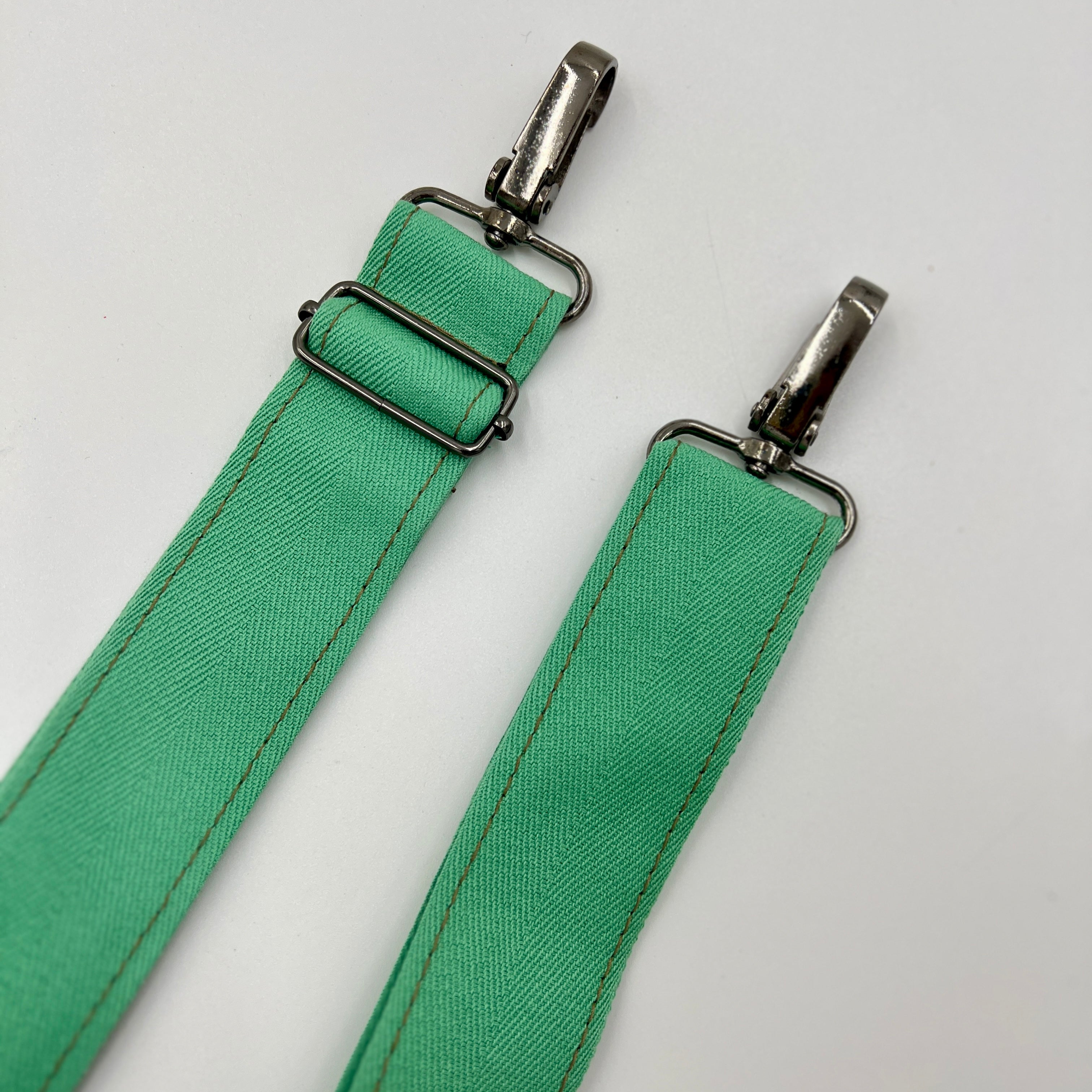 Green strap with metal hardware on a white background