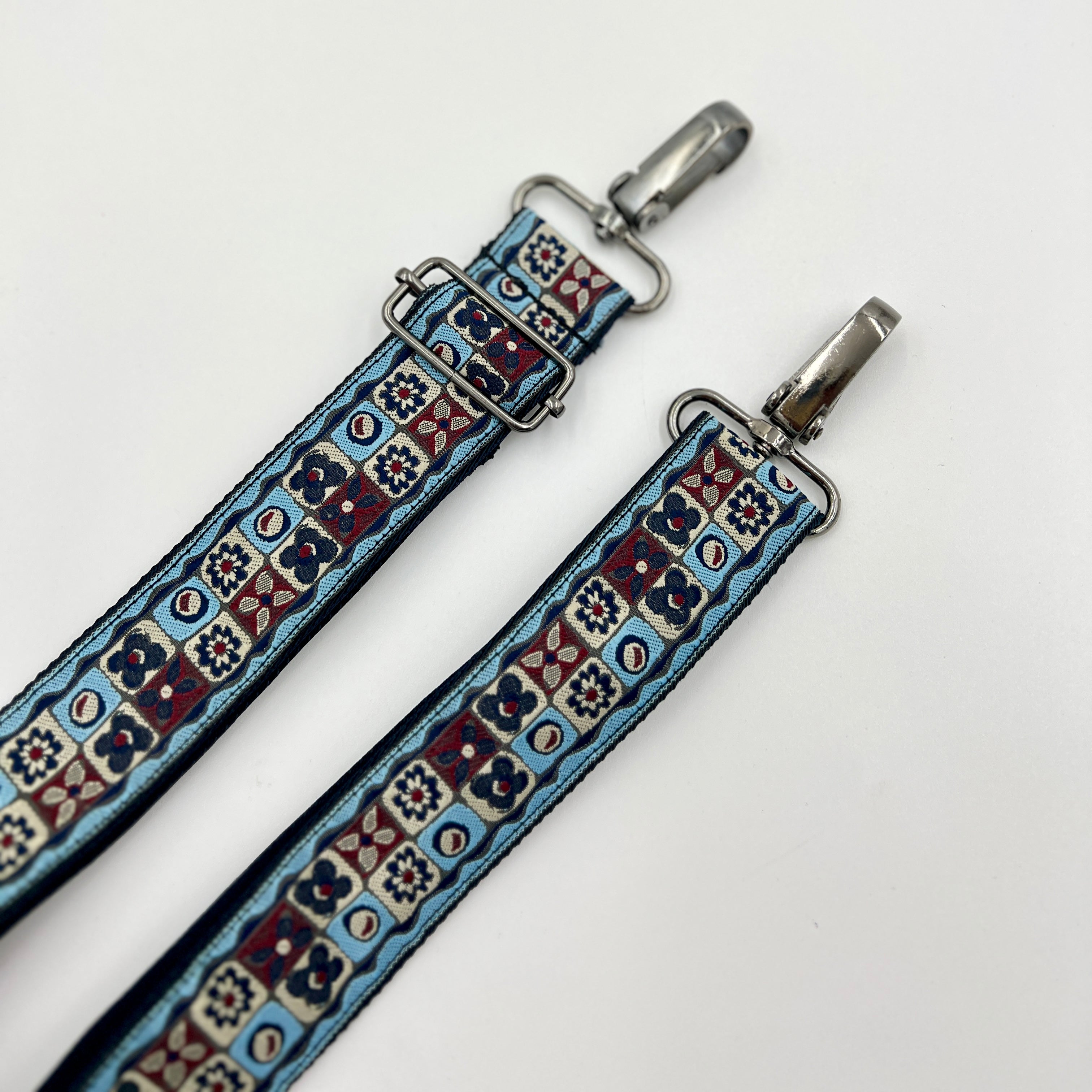 Decorative strap with patterned design and metal clasps on a white background