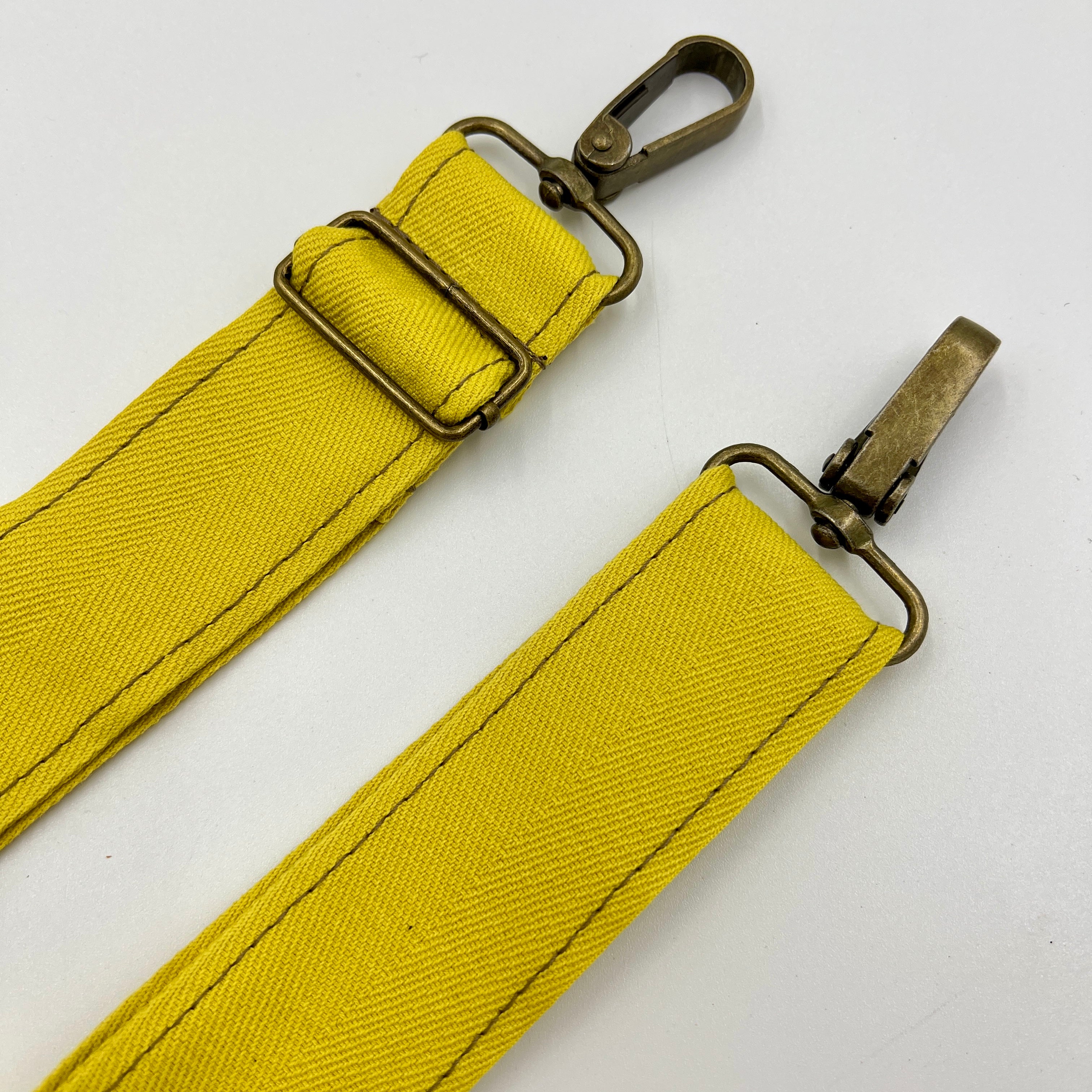 Yellow strap with brass hardware on a white background