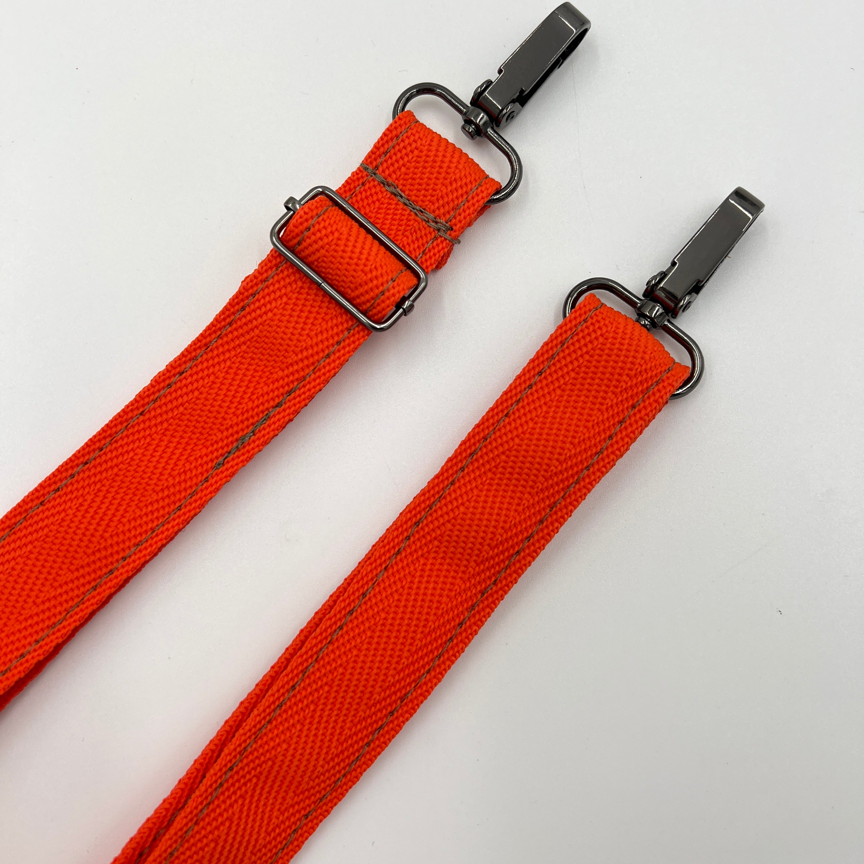 Two orange straps with metal buckles on a white background