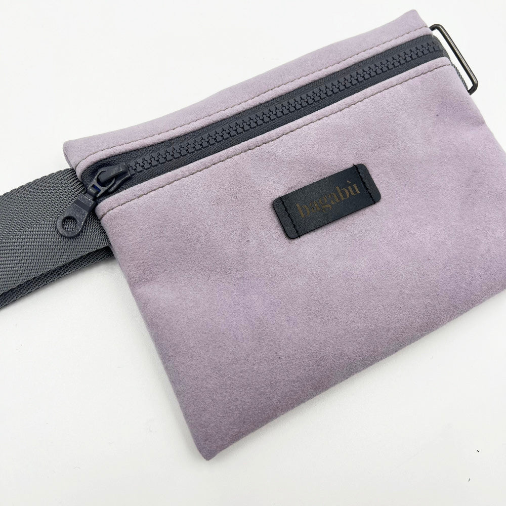 A purple waist bag with a black strap and a zipper closure, featuring a small branded tag on the front.