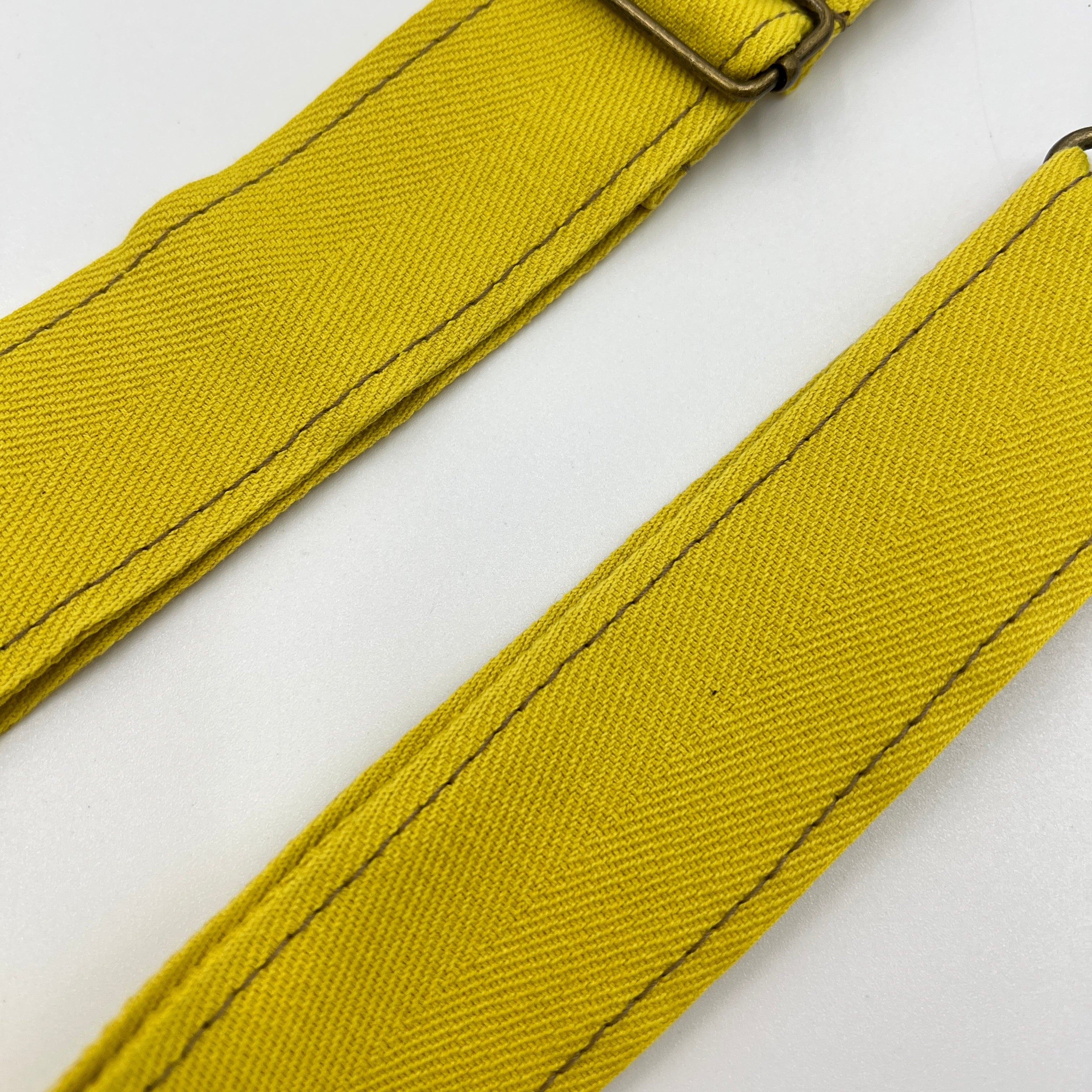 Two yellow straps with a metal buckle on a white background