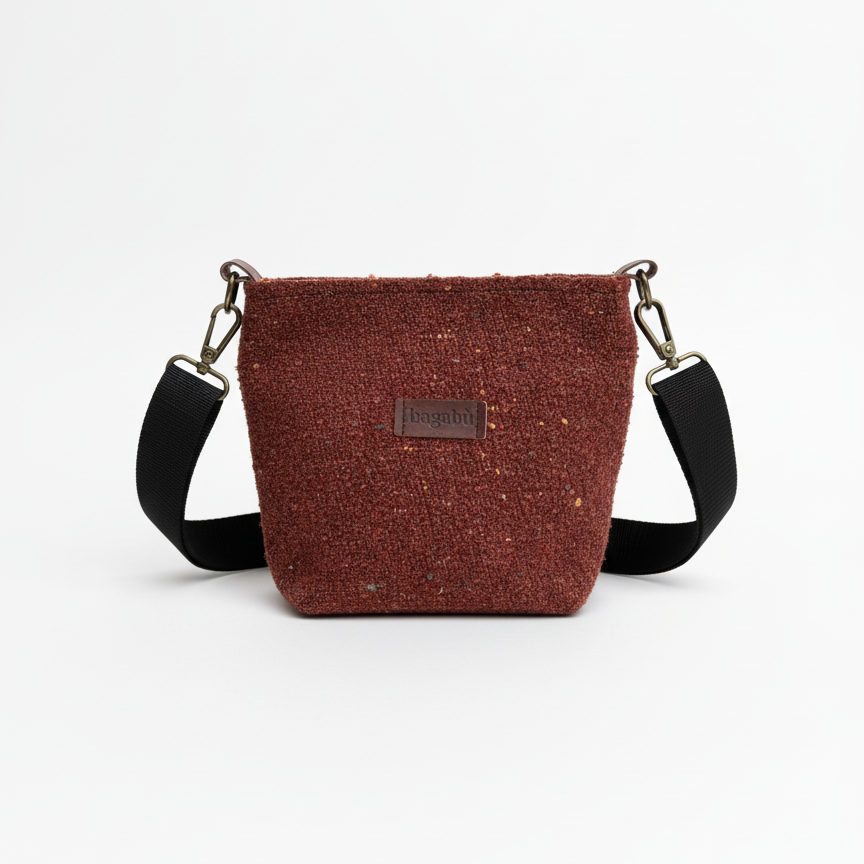 Brown crossbody bag with black straps on a white background