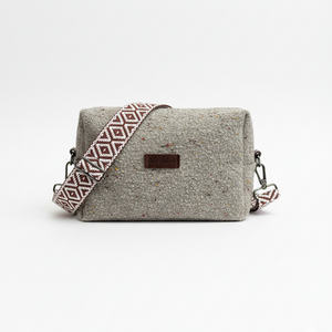 Gray textured handbag with a patterned strap on a white background