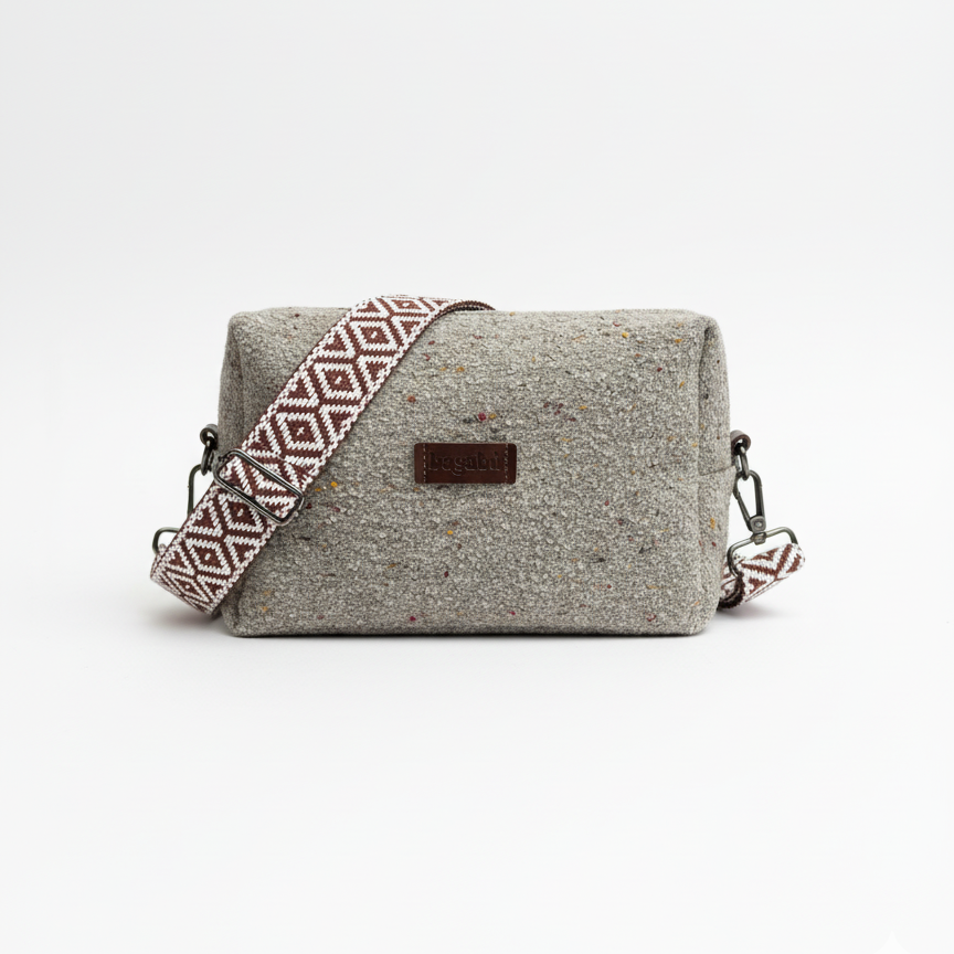 Gray textured handbag with a patterned strap on a white background
