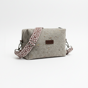 Gray textured handbag with a patterned strap on a white background