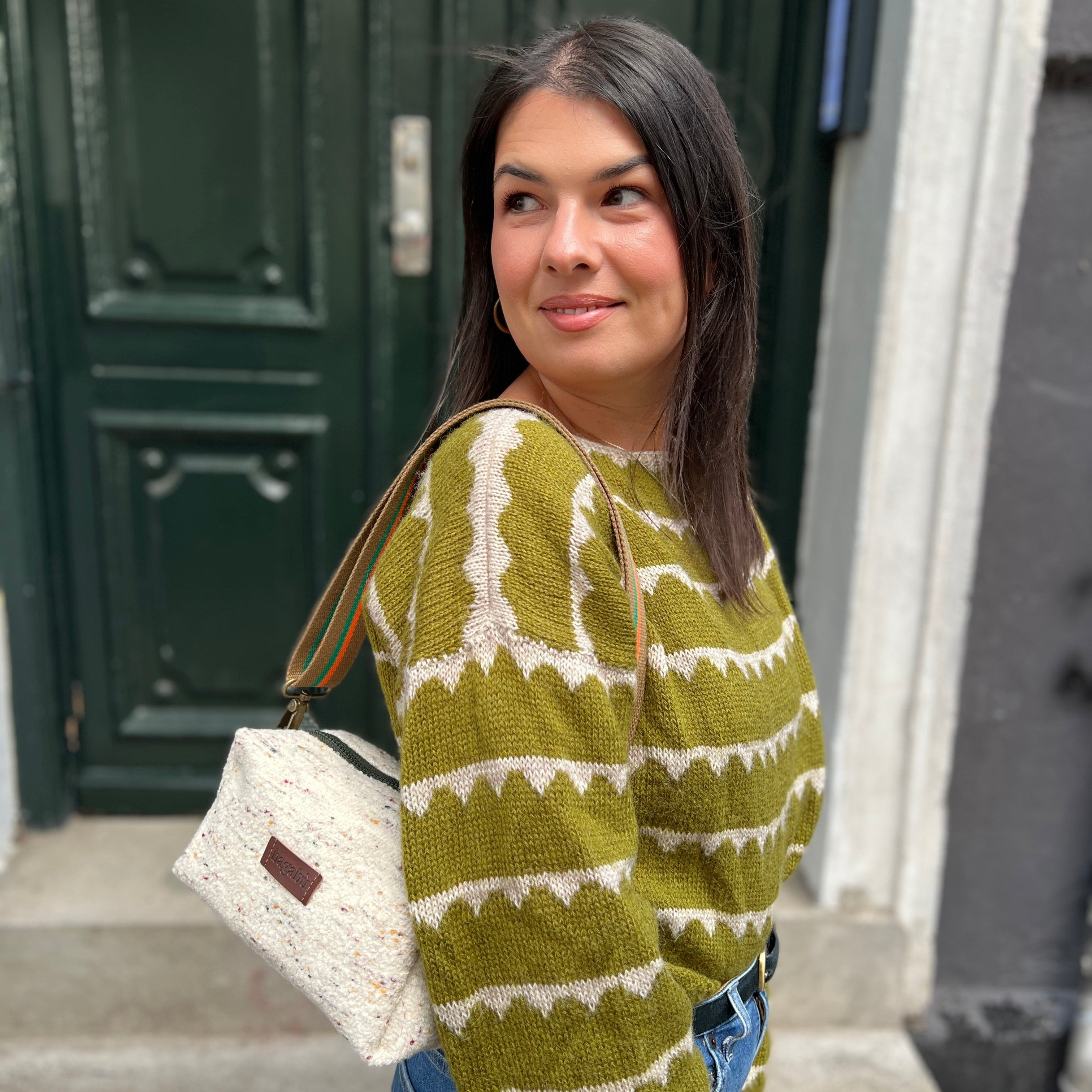 Woman wearing a green patterned sweater standing in front of a building entrance.