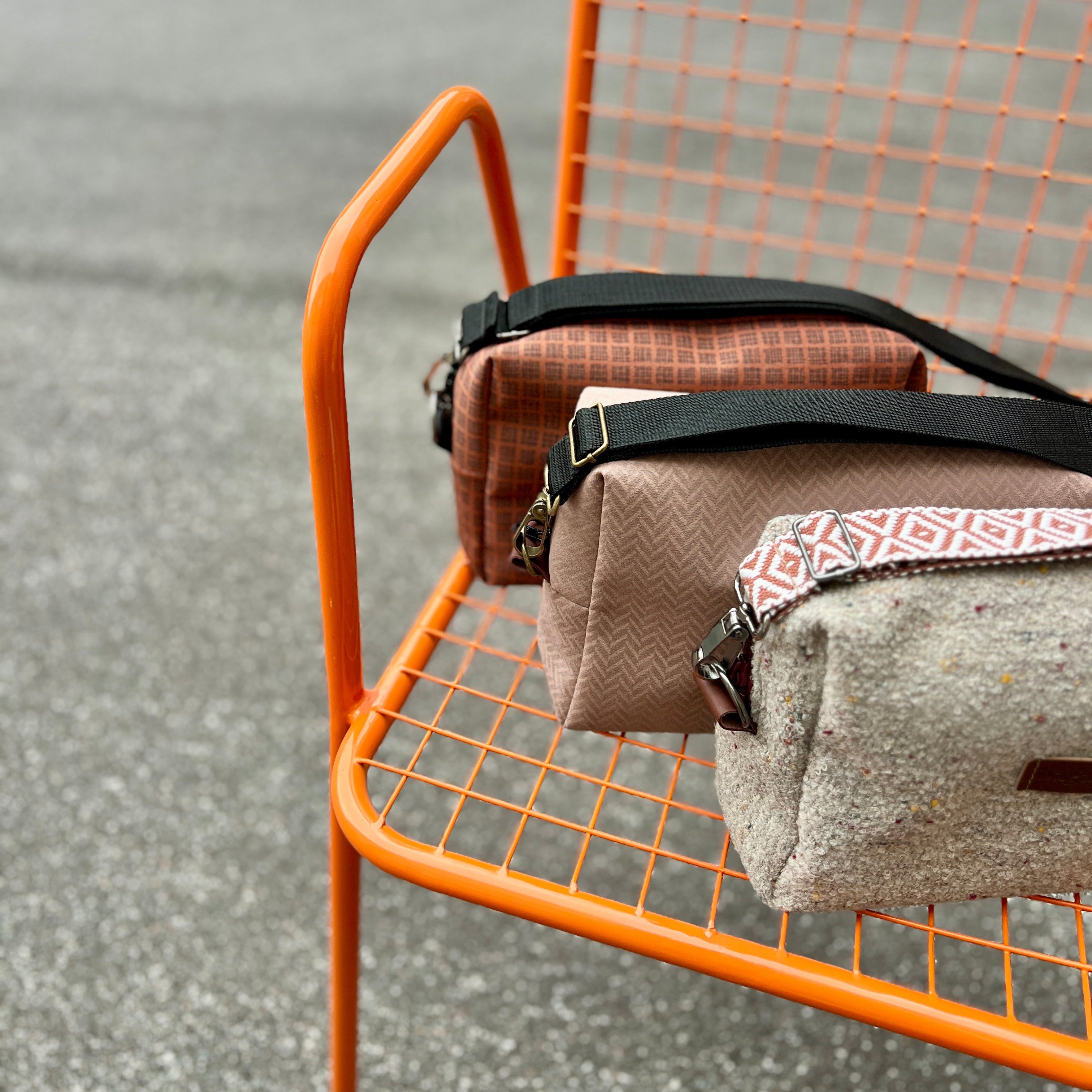 Three bags on an orange metal chair with a gray background