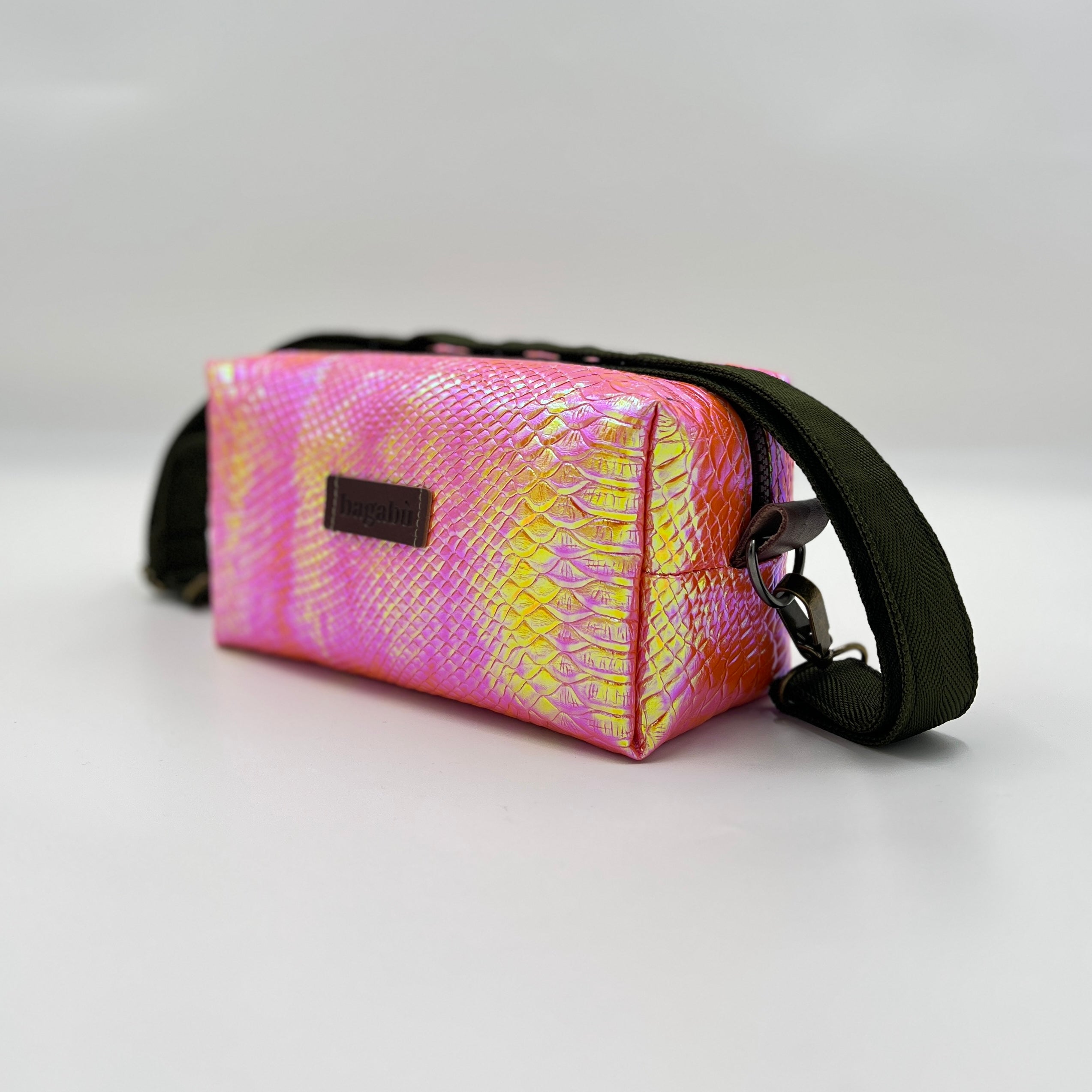 Pink and yellow patterned bag with a black strap on a light gray background