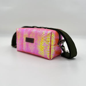 Pink and yellow patterned bag with a black strap on a light gray background