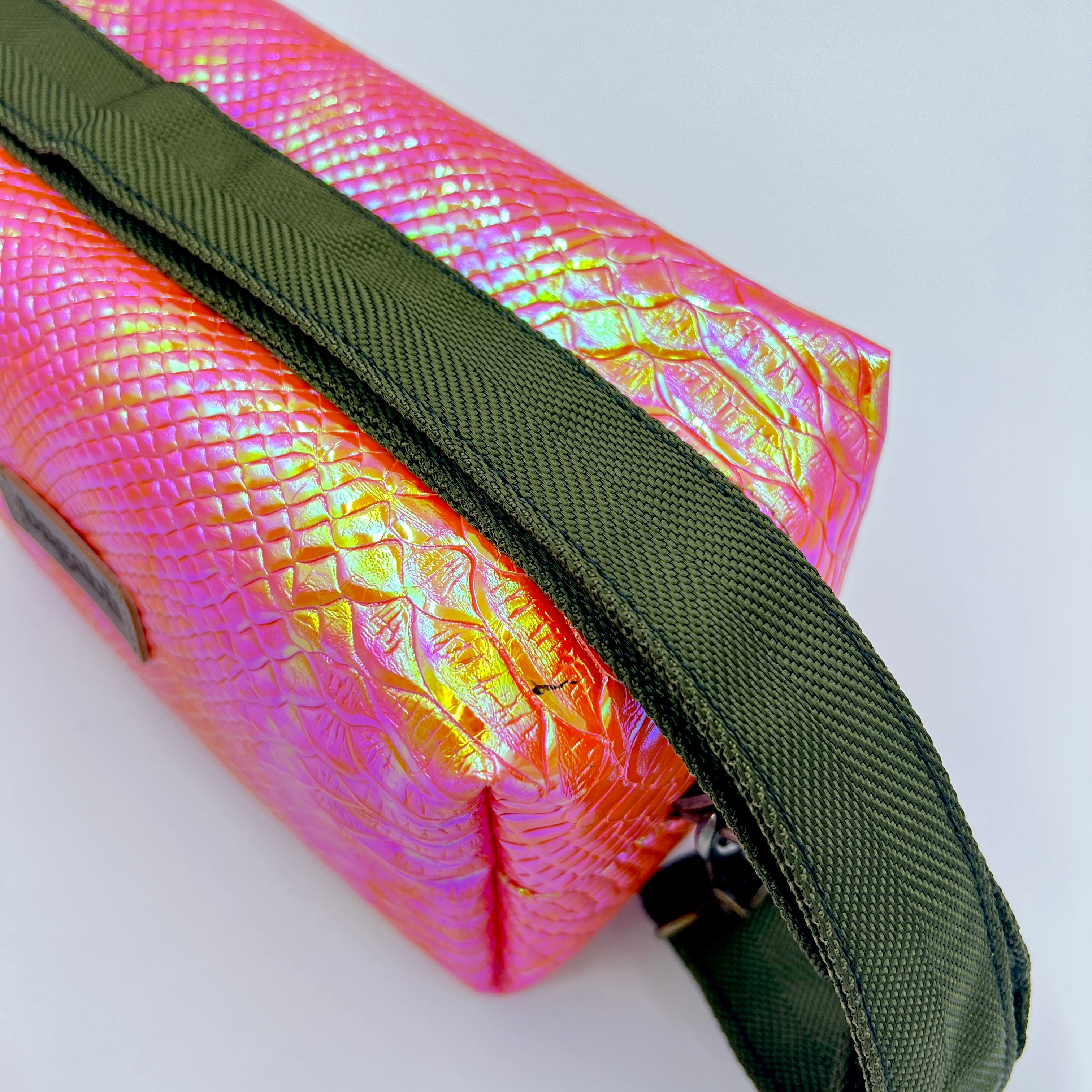 Iridescent pink and green clutch bag on a white background