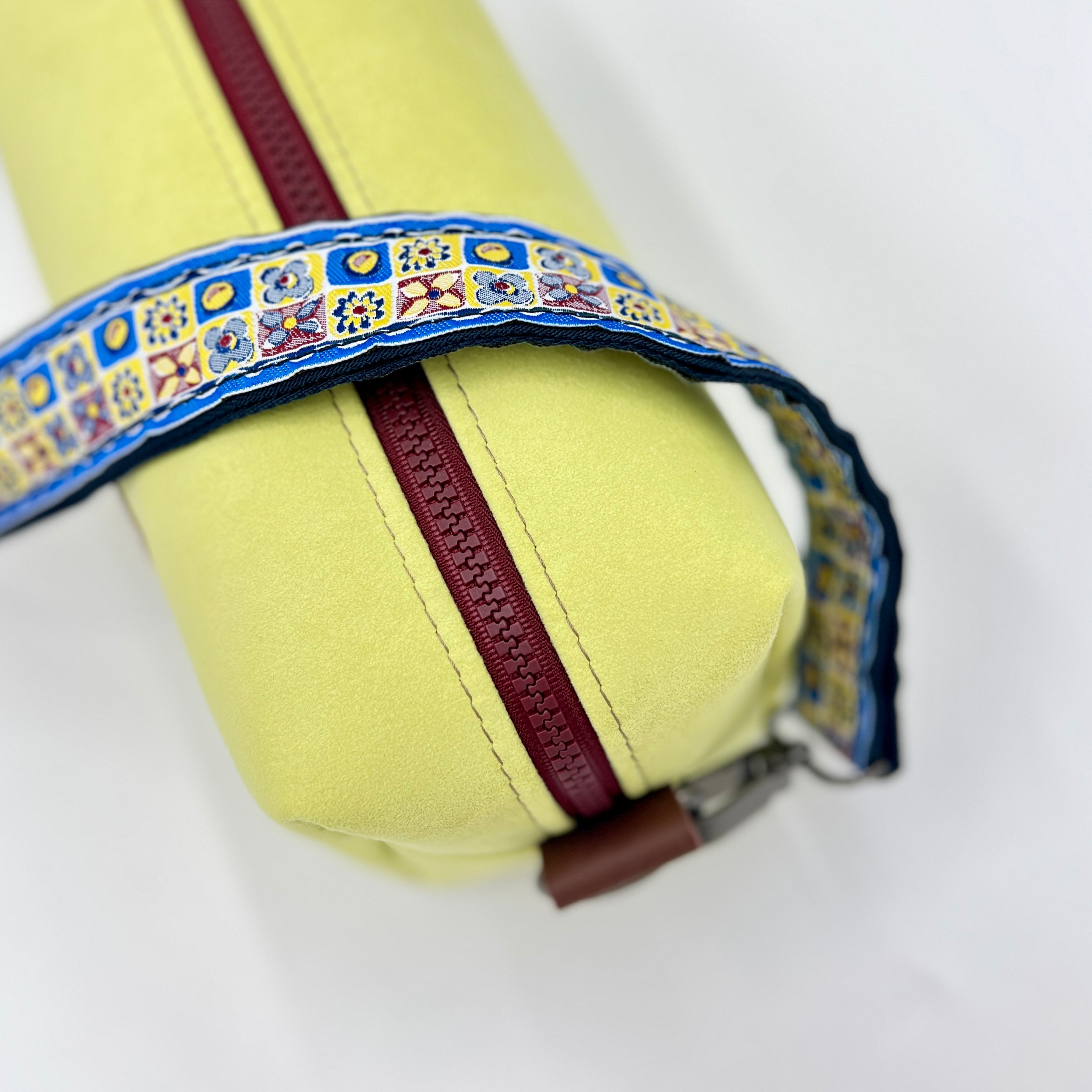 Yellow fabric roll with a colorful decorative band on a white background