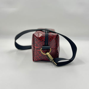 Small red and black patterned bag with a black strap on a light gray background
