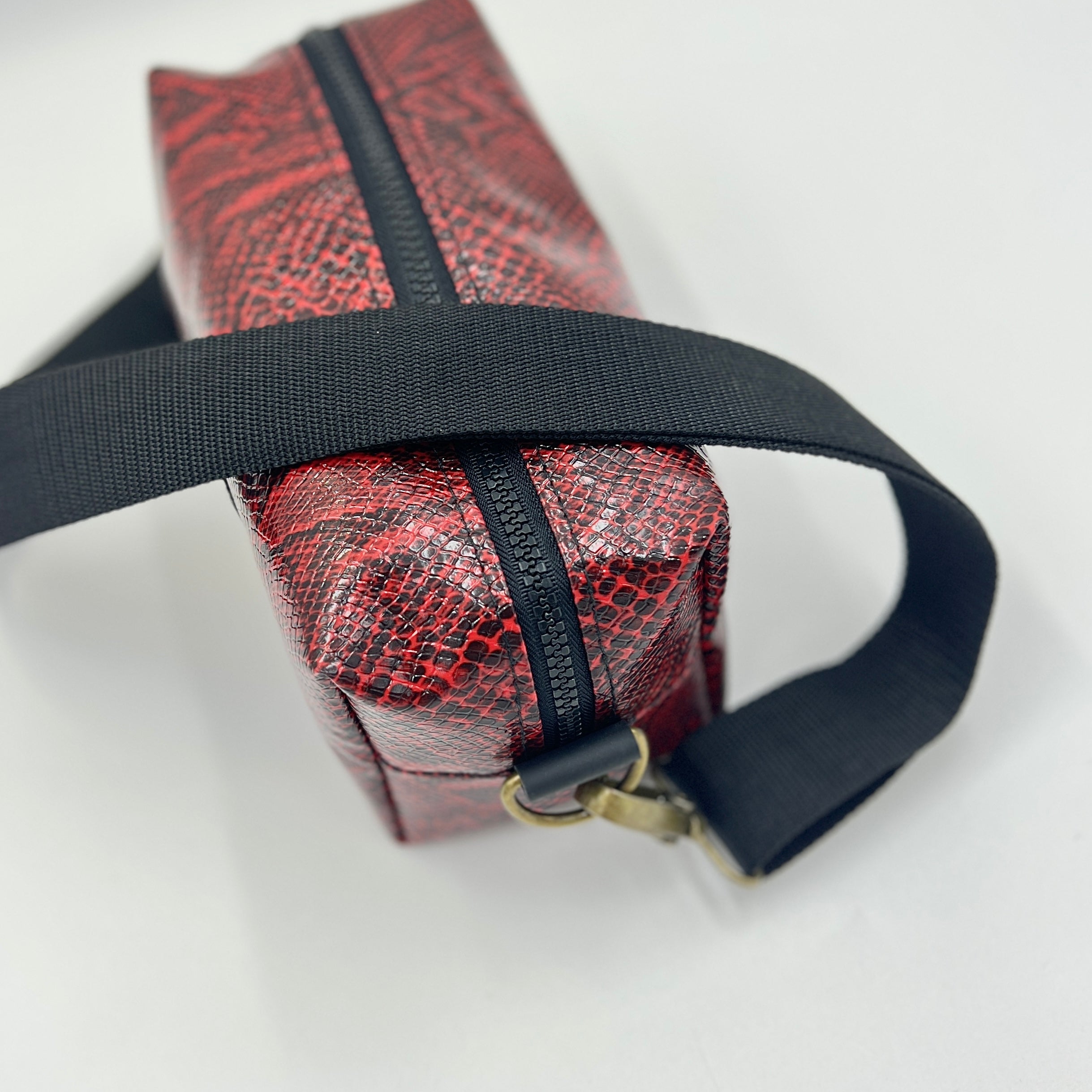 Red textured bag with a black strap on a white background
