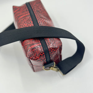 Red textured bag with a black strap on a white background